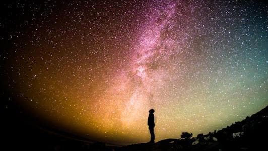 A photograph of a man Looking at the Milky Way